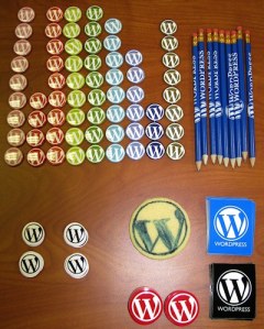 WordCamp swag - buttons, stickers, pencils, and cookie - photo by Lorelle VanFossen.
